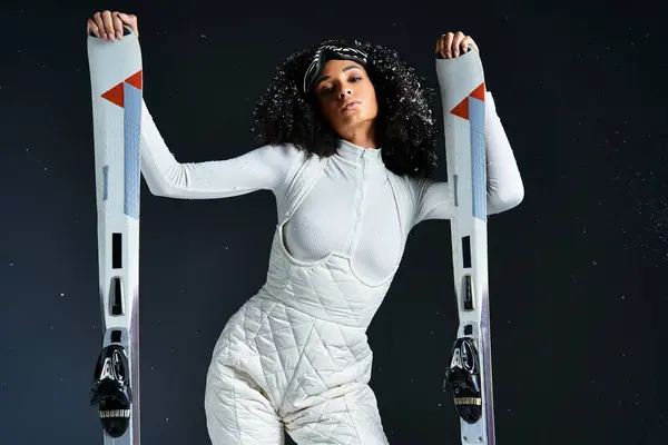 A stunning brunette woman poses confidently in a trendy ski suit, highlighting winter fashion in a studio. — Stock Photo
