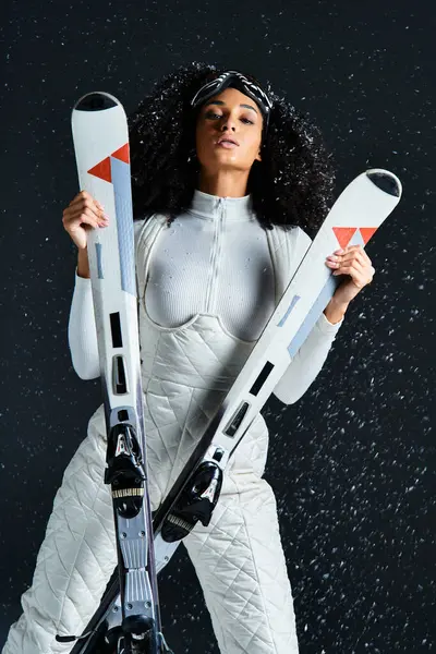 A beautiful brunette woman models a trendy ski suit, highlighting winter fashion in a dynamic studio setting. — Stock Photo