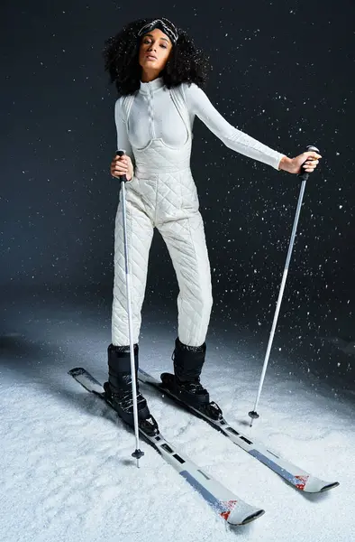 A beautiful brunette African American woman confidently models a chic ski outfit in a studio setting. — Stock Photo