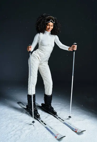 A beautiful brunette woman dressed in a stylish ski suit gracefully navigates a snowy indoor setting. — Stock Photo