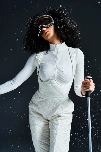 A beautiful brunette woman models winter fashion in a ski suit with elegant accessories in a studio. — Stock Photo