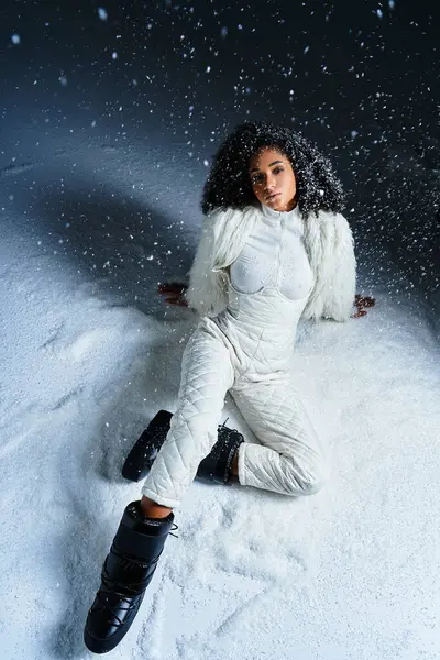 A beautiful woman gracefully poses in a white ski suit and chic faux fur, surrounded by swirling snowflakes. — Stock Photo