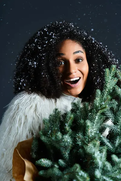 A stunning woman in a white ski suit with a faux fur jacket embraces winter, holding festive greenery joyfully. — Stock Photo
