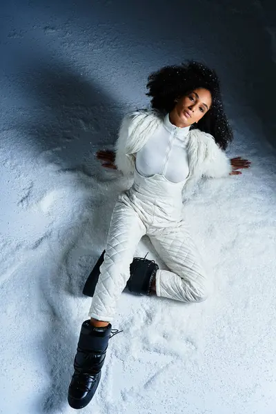 A fashionable woman relaxes in a white ski suit and faux fur jacket, embracing the snowy winter atmosphere. — Stock Photo