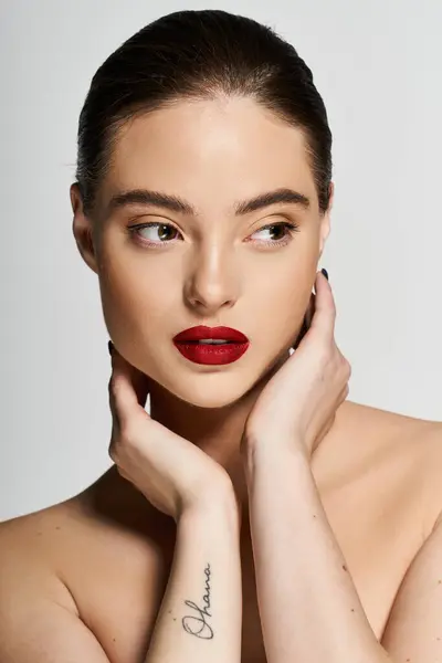 A graceful woman poses with her hands gently touching her face, exuding elegance and charm. — Stock Photo