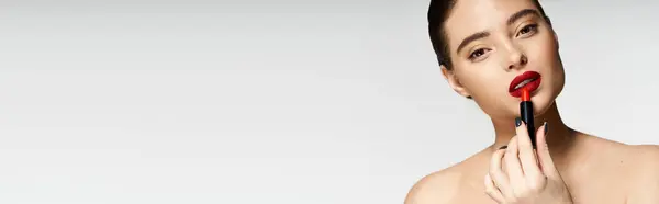 Eine schöne Frau verschönert ihren Look, indem sie auffällig roten Lippenstift selbstbewusst aufträgt. — Stockfoto
