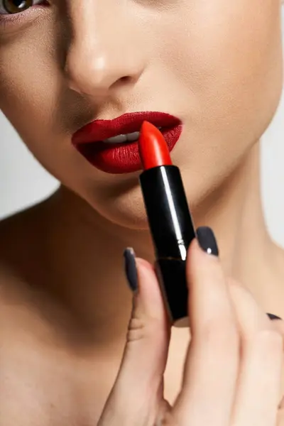 A woman applies bold lipstick, radiating confidence and style. — Stock Photo