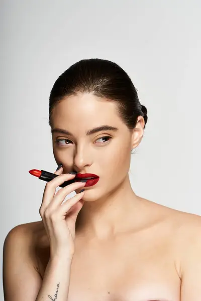The charming woman enhances her beauty while thoughtfully holding lipstick near her lips. — Stock Photo