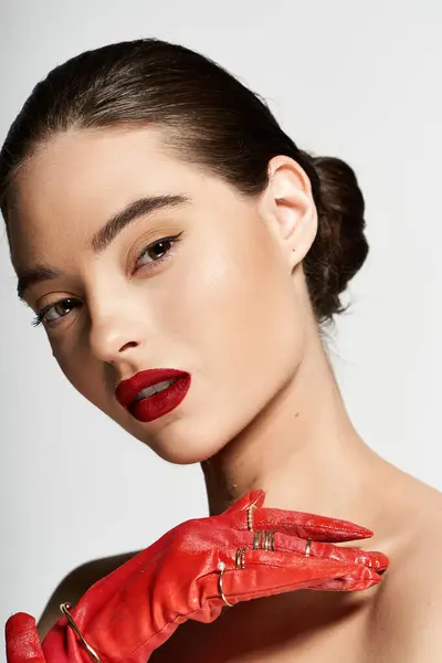 A stunning woman highlights her features with bold red gloves and captivating makeup. — Stock Photo