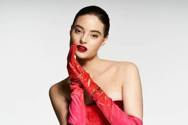 A stylish woman flaunts her red gloves and bold lip, radiating charm. — Stock Photo