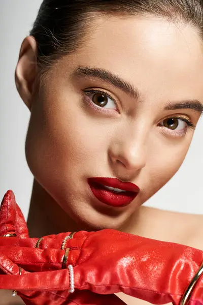 A striking woman with bold red lips poses gracefully while wearing elegant red gloves. — Stock Photo