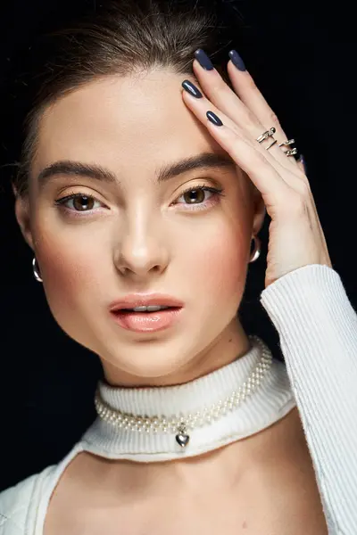 A stunning young woman highlights her beauty with stylish rings and a necklace, engaging the viewer. — Stock Photo