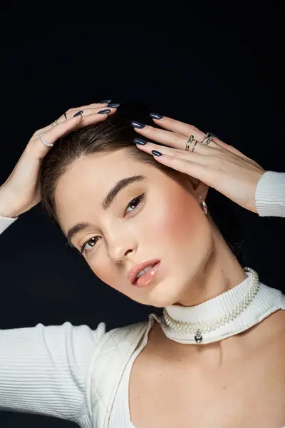 A graceful woman poses with her hands in her hair, exuding confidence and charm in a sleek outfit. — Stock Photo