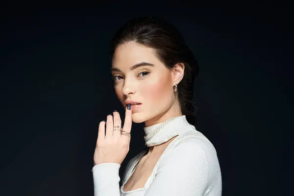 A stunning woman stands confidently, her hand gently touching her lips as she gazes intently. — Stock Photo