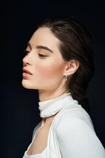 An elegant woman exhibits a serene expression against a dark background, highlighting her features. — Stock Photo