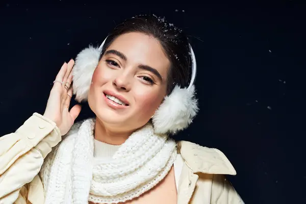 A cheerful woman in fluffy earmuffs and a scarf smiles in the winter ambiance. — Stock Photo