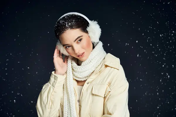 A charming lady enjoys the winter atmosphere with a cozy scarf and ear muffs while smiling. — Stock Photo