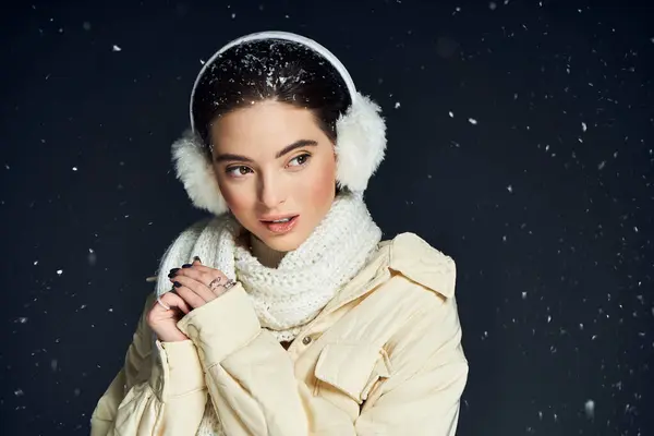 A lovely woman dressed warmly enjoys the gentle snowfall while smiling softly outside in winter. — Stock Photo