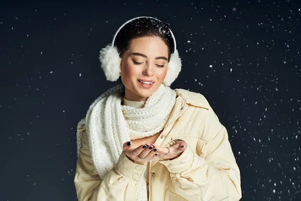 Una donna gioiosa gioca con i fiocchi di neve cadenti mentre è impacchettata in abiti invernali caldi. — Foto stock