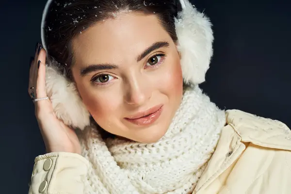 Una bella donna abbraccia la stagione invernale con eleganti paraorecchie e una sciarpa lavorata a maglia. — Foto stock