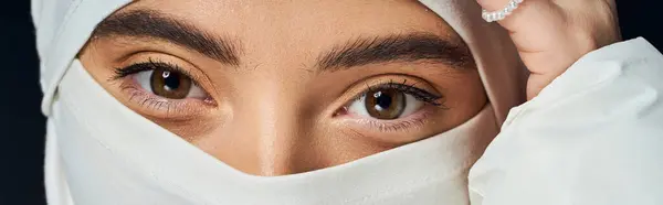 A woman showcases her grace and beauty, framed by a delicate headscarf while softly gazing. — Stock Photo