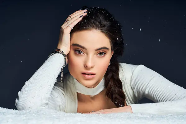 A stunning woman with a braided hairstyle rests her hand on her head, surrounded by snowflakes. — Stock Photo