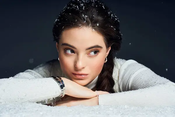 Esta impresionante mujer mira pensativamente mientras descansa en un entorno nevado. - foto de stock