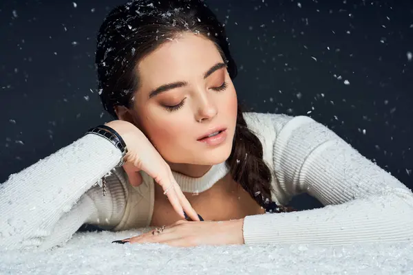 Una mujer encantadora disfruta de un momento tranquilo mientras descansa sobre nieve suave con copos de nieve que caen a su alrededor.. - foto de stock