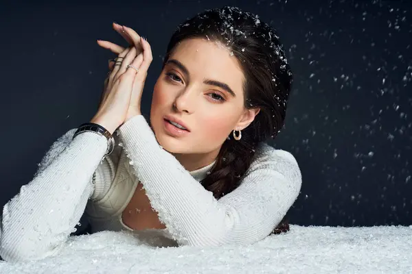 La mujer mira pensativamente mientras los copos de nieve se deslizan suavemente a su alrededor en un ambiente acogedor. - foto de stock