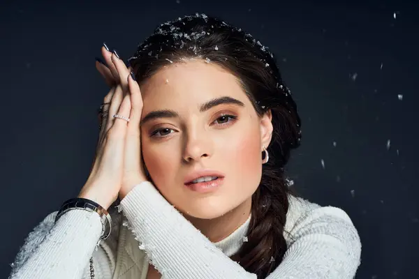 A beautiful woman with a gentle expression rests her head on her hands as snow falls around her. — Stock Photo