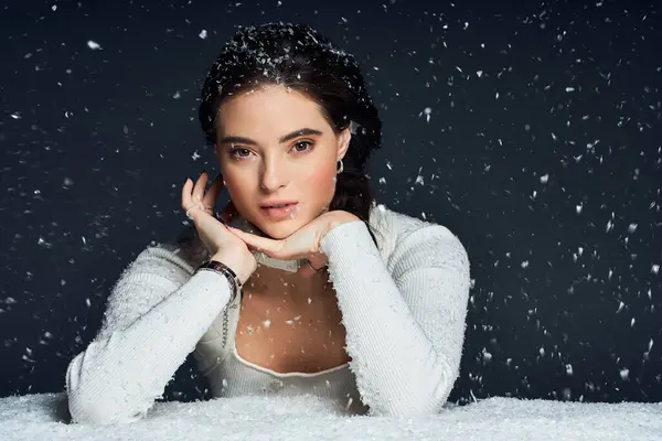 A graceful woman gazes thoughtfully as snow delicately falls around her in winter bliss. — Stock Photo