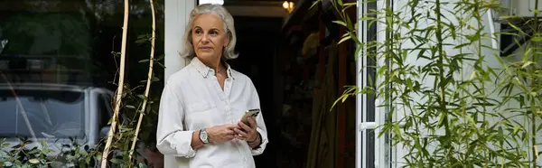 A poised woman enjoys a moment outside her home, connected to nature and technology. — Stock Photo