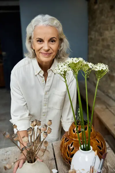 A joyful woman works with fresh flowers, showcasing her creativity and appreciation for nature. — Stock Photo