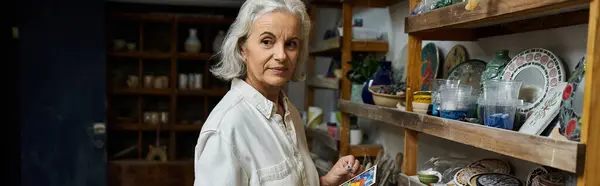 A skilled artist organizes her colorful ceramic collection in a charming art studio. — Stock Photo