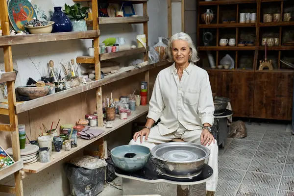 A mature woman creates unique pottery pieces in her artistic, tool filled space. — Stock Photo