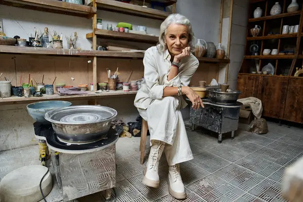 A skilled artisan engages in pottery techniques while surrounded by her creative workspace. — Stock Photo