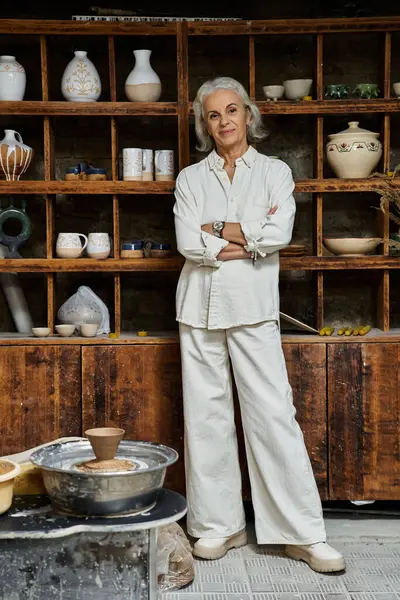 Una donna orgogliosa e creativa sta accanto alle sue creazioni in ceramica nello studio. — Foto stock