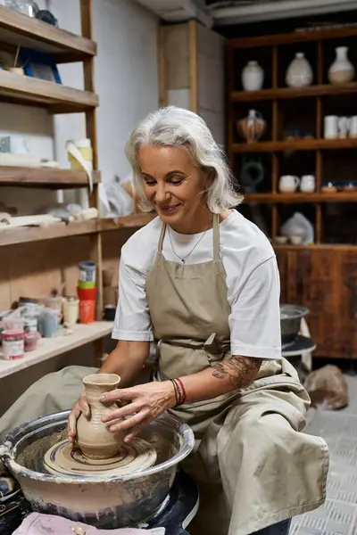 A skilled mature woman crafts a delicate pottery piece, showcasing her artistic talent and joy. — Stock Photo