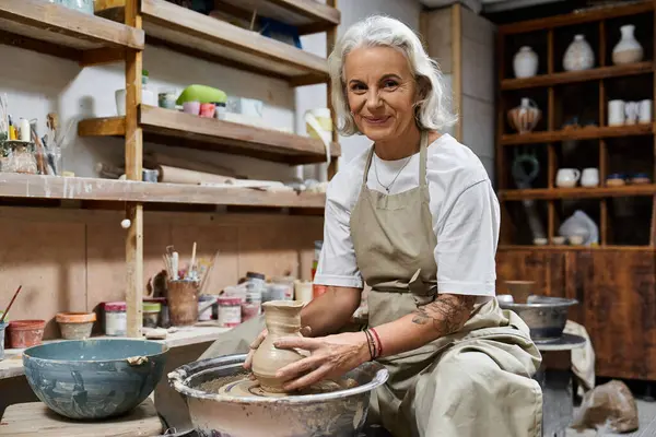 A skilled artisan is shaping a clay pot with care in her inviting workshop. — Stock Photo