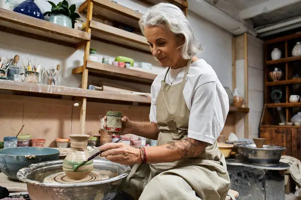 A skilled mature woman carefully crafts pottery while enjoying her creative process. — Stock Photo