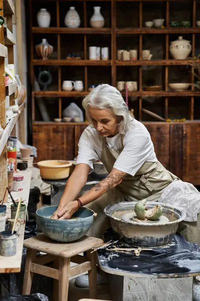 Ein fokussierter Künstler formt in einer rustikalen Werkstatt mit Kunstwerkzeugen Ton auf einer Töpferscheibe. — Stockfoto