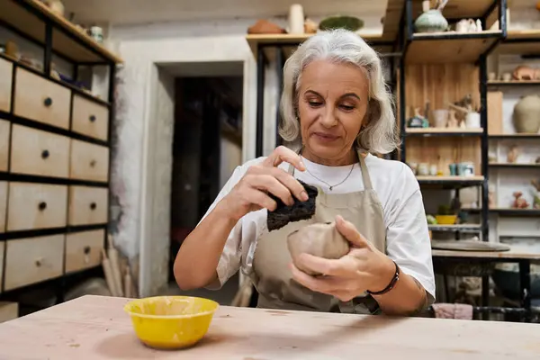 A skilled artisan shapes clay carefully, immersed in her pottery craft, surrounded by art tools. — Stock Photo