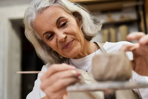 A skilled artisan meticulously shapes clay while smiling in her inviting craft space. — Stock Photo