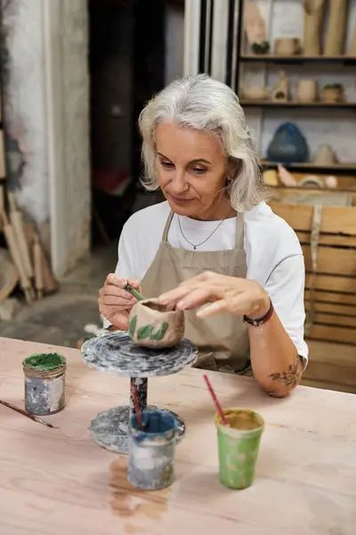 A skilled potter carefully paints a delicate design on her handmade pottery in an artistic studio. — Stock Photo
