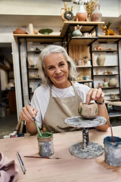 A talented woman works on pottery, smiling warmly as she shapes a piece in her studio. — Stock Photo