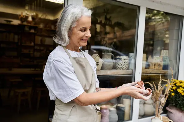 The skilled artisan proudly holds a handmade pottery piece while smiling warmly. — Stock Photo