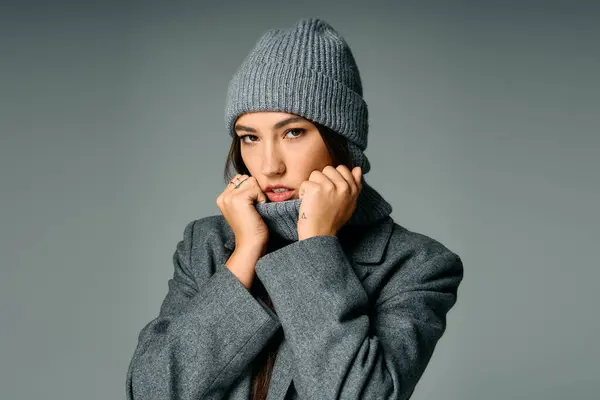 A young and attractive woman models fashion in a cozy gray outfit while showcasing her style. — Stock Photo