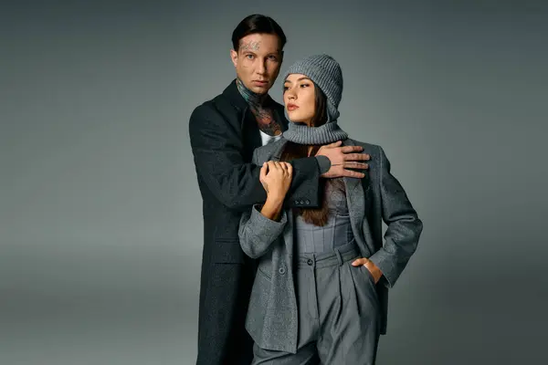 Un jeune couple à la mode présente des vêtements gris modernes et des poses frappantes ensemble. — Photo de stock