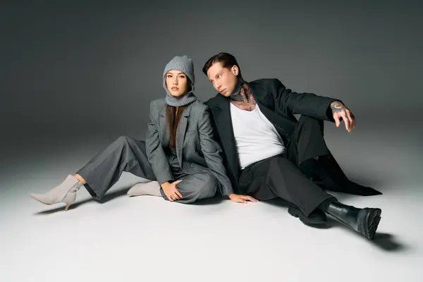 A fashionable duo sits casually on a smooth surface, showcasing contemporary styles together. — Stock Photo
