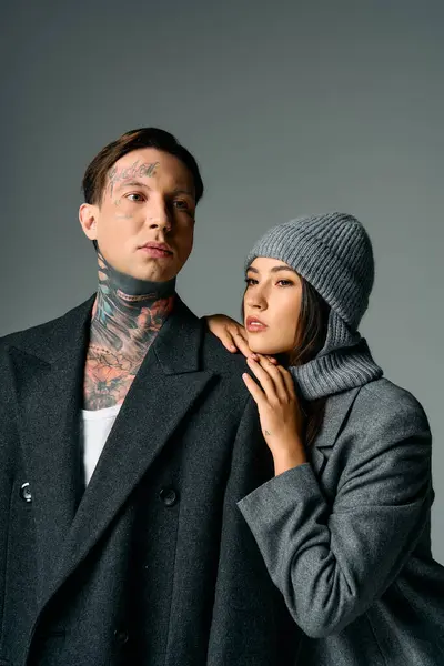 Una giovane coppia abbraccia, mostrando il loro abbigliamento alla moda e tatuaggi in una posizione chic. — Foto stock